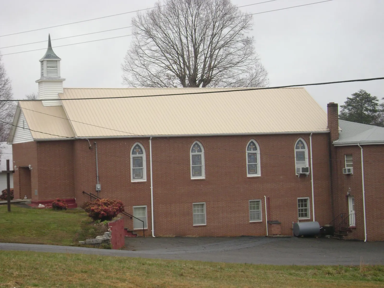New tan metal roof on a brick church with a white steeple in Arlington